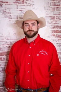 PIcture of Zach Smith - in Red oxford with Crooked river logo on it - and taupe cowboy hat