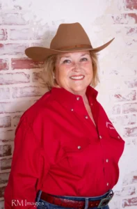 PIcture of Susie Pape - in Red oxford with Crooked river logo on it - and medium brown cowboy hat
